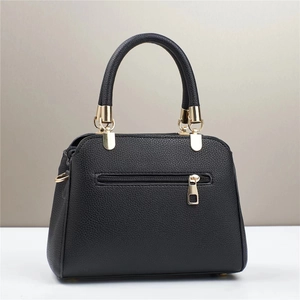 Detail view of black litchi grain leather handbag with gold hardware and back zipper pocket