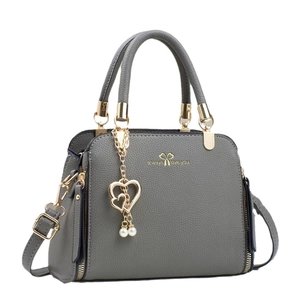 Fashionable grey lychee leather handbag with heart pendant and gold hardware on white background