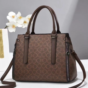 Detail view of brown leather handbag with chain print and decorative side zippers