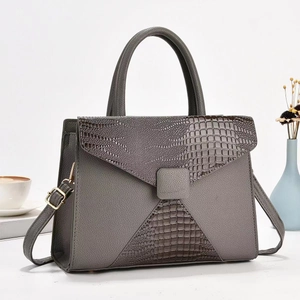Detailed view of grey faux leather handbag featuring faux crocodile texture and gold hardware