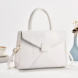 Detail of white crocodile pattern handbag with flap closure and elegant top handle
