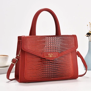Detail of red crocodile texture handbag with heart metal buckle and adjustable strap