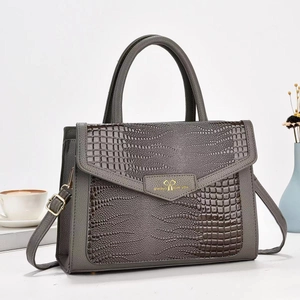 Close-up of gray crocodile-embossed leather handbag with gold heart buckle detail