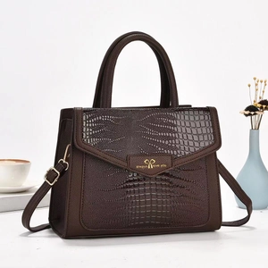Macro detail of dark brown crocodile embossed leather handbag with golden hardware