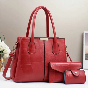 Dettaglio del set di borse rosse con cuciture geometriche e chiusure dorate in oro