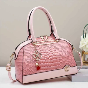 Dettaglio borsa a mano rosa motivo coccodrillo con hardware dorato e ciondolo a quadrifoglio
