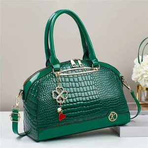 Dettaglio della borsa verde scuro effetto coccodrillo con ciondolo a quadrifoglio d'oro
