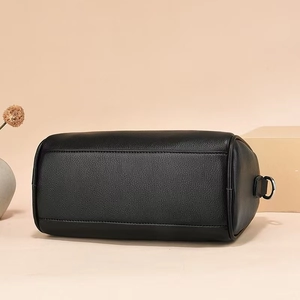 Detail view of black pebble leather texture and metal rings on a stylish cylinder bag