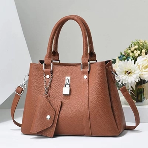 Détail de la texture cuir grainé marron du sac à main avec boucle métallique argentée