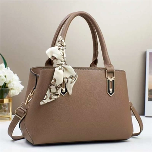 Detail of brown litchi pattern leather handbag with gold hardware and decorative silk scarf