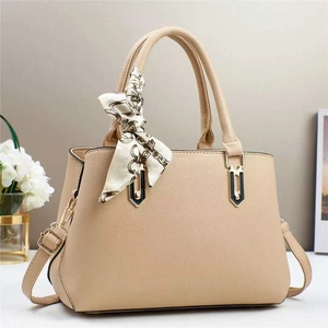 Detail of beige lychee texture handbag with silk scarf and gold-tone hardware accent