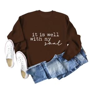 Flat lay of brown 'it is well with my soul' sweatshirt with jeans and white sneakers