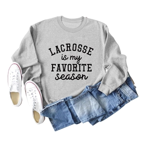 Flat lay of a grey Lacrosse sweatshirt styled with denim shorts and white sneakers
