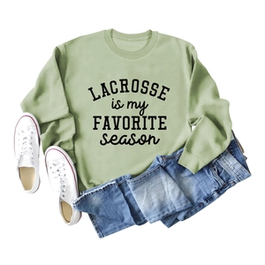 Flat lay of sage green Lacrosse sweatshirt with blue jeans and white canvas shoes