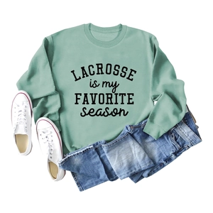 Sage green lacrosse sweatshirt styled with blue jeans and white canvas sneakers