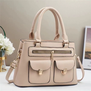 Detail of beige lychee leather tote bag with gold turn-lock pockets and adjustable strap