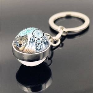 Macro detail of silver wolf and dreamcatcher pattern inside spherical glass pendant keychain