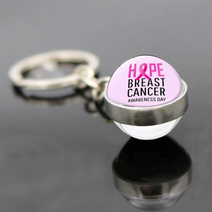 Detail of breast cancer awareness keychain with pink ribbon and Hope slogan on black surface