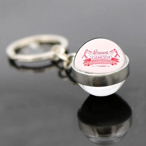 Pink ribbon breast cancer awareness glass ball keychain with metal ring on black background