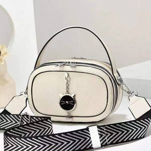 Cream-white crossbody bag with black trim, cat charm, and zig-zag pattern strap