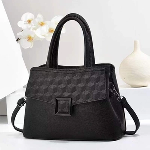 Close-up of black tote bag featuring geometric embossed flap and pebble grain leather