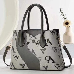 Détail du sac cabas trapèze gris avec imprimé monogramme et boucles métalliques dorées