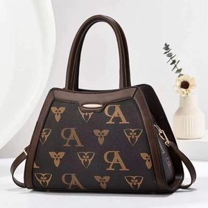 Close-up of patterned faux leather handbag with golden zippers and floral monogram prints