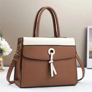 Detail of contrasting brown and beige leather handbag with tassel and gold hardware