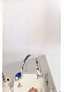 Dettaglio del ricamo a fiori arancioni e farfalla su una borsa a mano beige