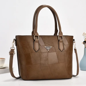 Dettaglio di una borsa a secchiello in pelle PU marrone con patchwork e logo dorato