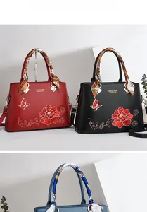 Dettaglio ricamo floreale e foulard in seta su borse di lusso in pelle opaca