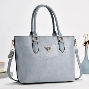Dettaglio di borsa tote in pelle patchwork azzurra con logo dorato e tracolla