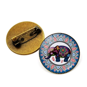 Detail of round brooch showing colorful elephant pattern and bronze metal safety pin back