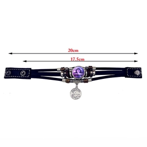Detalle de pulsera de cuero trenzado con signo Libra luminoso y colgante de metal Escorpio