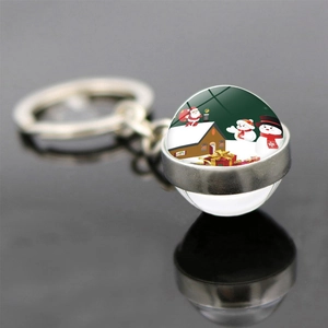 Macro shot of double-sided glass ball keychain with Christmas santa and gift box scenes