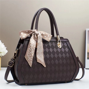 Detail of quilted dark chocolate shoulder bag with golden hardware and dotted silk scarf