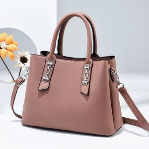 Detail view of pink leather handbag featuring a silver chain and detachable shoulder strap