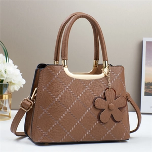 Brown quilted leather tote bag with elegant top handle and flower charm detail