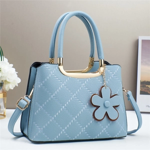 Detail of light blue lychee texture tote bag with gold handle and floral charm