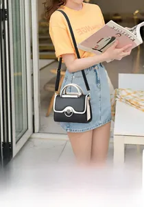 Close-up of contrast stitching handbag with gold metal clasp on a stylish model
