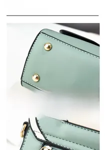 Detail view of mint green handbag featuring golden protective studs and color-block stitching