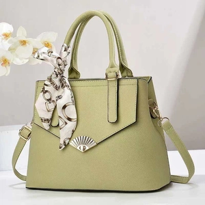 Close-up of sage green litchi texture tote bag with elegant silk scarf handle and metal clasp