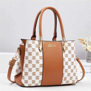 Close-up of contrast patchwork tote bag with brown leather, checkered pattern and gold hardware