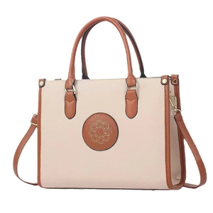 Two-tone beige and brown patchwork handbag with crossbody strap and gold floral pattern