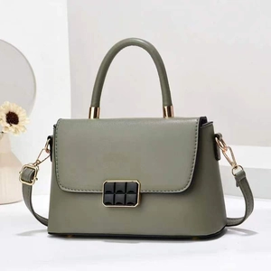 Detail of dark green leather handbag with gold metal clasp and textured mesh buckle