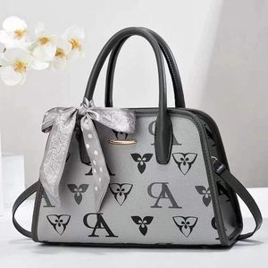Detailed view of gray patterned handbag with decorative scarf and golden logo