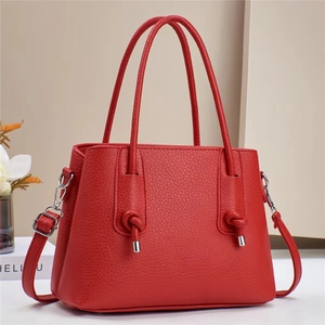 Detail of red lychee textured handbag showing silver hardware and adjustable shoulder strap