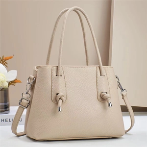 Close-up of beige lychee grain leather tote bag with elegant side knots and shoulder strap