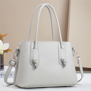 Detail view of grey litchi texture leather tote bag with silver hardware on minimal background