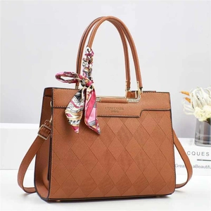 Detail of brown quilted leather bucket bag with silk scarf and gold JIMSH logo hardware